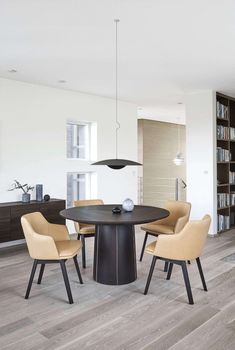 a dining room table with four chairs and a bookcase in the backround