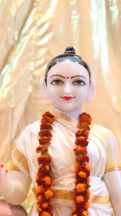 a white statue with orange garlands around it's neck