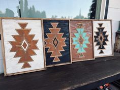 three framed wooden art pieces sitting on top of a table in front of a window