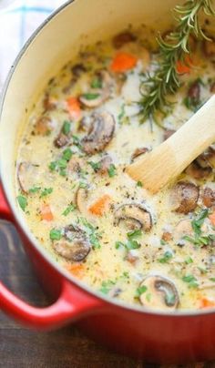 a red pot filled with mushroom soup on top of a wooden table