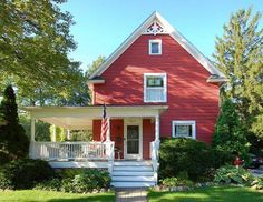 a red house with white trim and stairs leading up to the front door on a sunny day