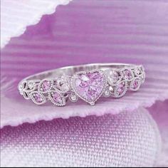 a pink heart shaped diamond ring on top of purple fabric