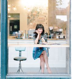 a woman sitting at a table in front of a window