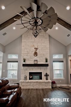 a living room with a fireplace, couch and ceiling fan in it's center