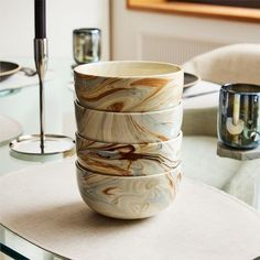 four marbled bowls sitting on top of a glass table in front of a painting