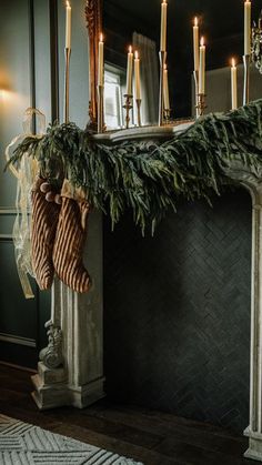 stockings hanging from the mantle in front of a mirror with candles and garland on it