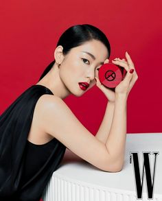 a woman holding a red object in front of her face with the word w on it