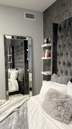 a bedroom with a bed, mirror and shelving unit in the middle of it