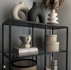 a shelf filled with vases and books on top of each other next to a basket