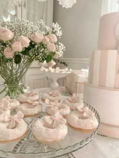 a table topped with lots of cupcakes covered in frosting next to a vase filled with flowers