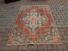 an old rug is laying on the ground in front of a brick wall and sidewalk