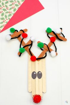 popsicle reindeer craft with pom - poms on the nose and antlers