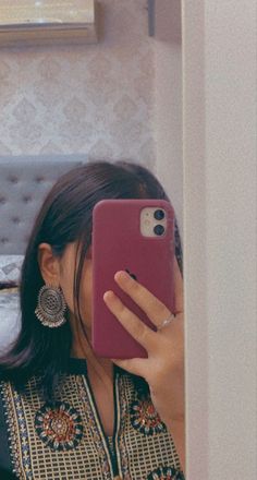 a woman taking a selfie with her cell phone in front of her earring