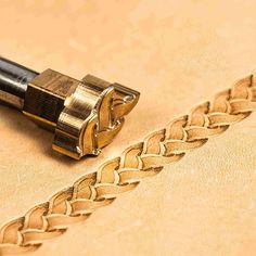 a close up of a gold colored object on a beige surface with a black handle