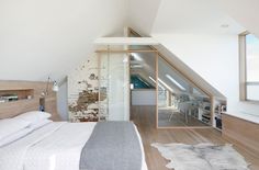 an attic bedroom with white walls and wood flooring is pictured in this image, the bed has been made