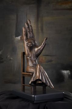 a bronze statue of a hand on a wooden chair