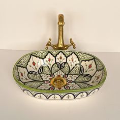 a decorative sink with a golden faucet on the top and an ornate design