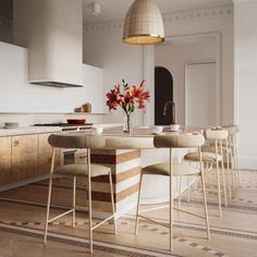 a kitchen with white walls and wooden flooring has an island table surrounded by stools