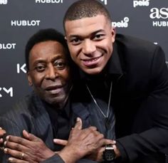 two men hugging each other in front of a red carpeted wall with the words hublot on it