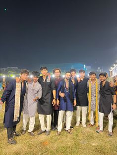 a group of men standing next to each other on top of a grass covered field