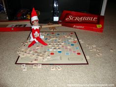 an elf sitting on top of a board game with scrabble letters all over it