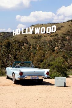 an old car is parked in front of the hollywood sign