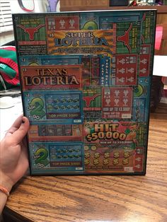 a person holding up a board game on top of a wooden table