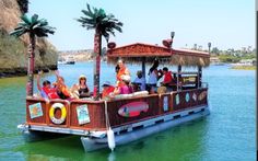 people are riding on the back of a boat in the water with palm trees and thatched roof