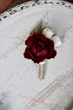 a boutonniere with a red flower on it sitting on a white table