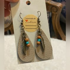 a pair of earrings that are on top of a piece of paper with a tag