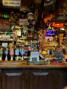 a woman standing behind a bar filled with lots of bottles