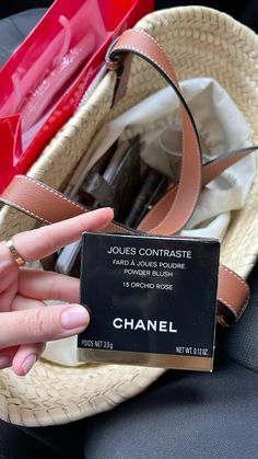 a woman's hand holding up a chanel card in front of her purse