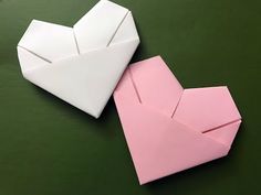 two origami hearts sitting on top of each other, one pink and one white