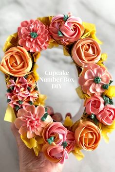 a hand holding a fake flower wreath with the words cupcake number box diy