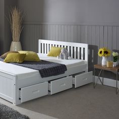 a white bed with two drawers underneath it and a stuffed animal sitting on the side