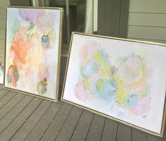 two framed paintings sitting on top of a wooden floor