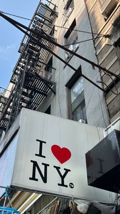 a sign that says i love new york on the side of a building with fire escapes