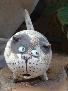 a cat statue sitting on top of a wooden stump