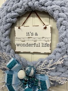 a blue and white wreath hanging on a door with it's a wonderful life sign