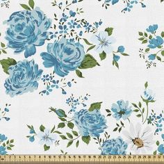 blue flowers on white fabric with green leaves and stems in the center, next to a ruler