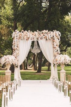 an outdoor ceremony with white drapes and flowers