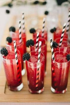 red drinks with blackberries are lined up on a tray and ready to be served