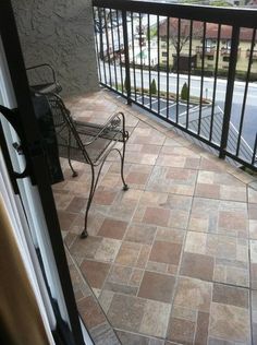 a balcony with a metal chair and table on it, looking out onto the street