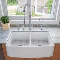 a double white kitchen sink in front of a window