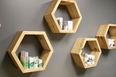 three wooden hexagonal shelves on the wall with soaps and lotions in them