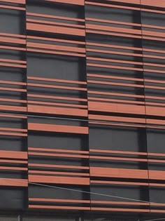 an airplane is flying in front of a building with red and black stripes on it