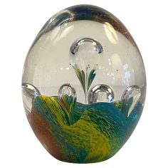 a clear glass vase with colorful designs on the outside and inside, sitting on a white surface