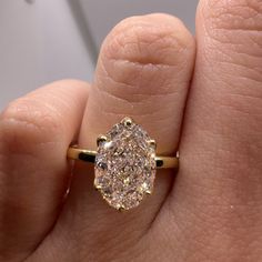 a close up of a person's hand holding a ring with a diamond in it