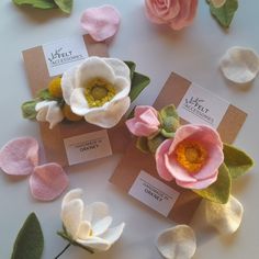 three different types of felt flowers on top of each other with leaves and tags around them