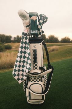 a golf bag sitting on top of a green grass covered field next to a white and black checkered towel